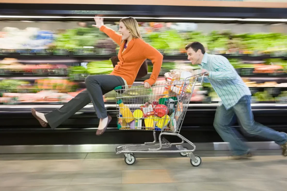 Man pushing woman in grocery store shopping cart